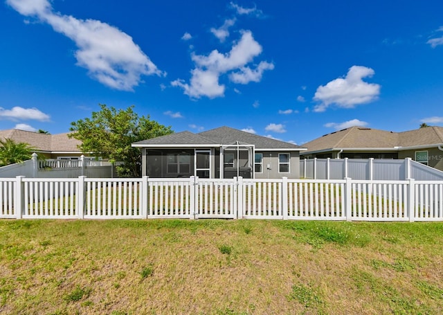 rear view of house with a lawn and a sunroom