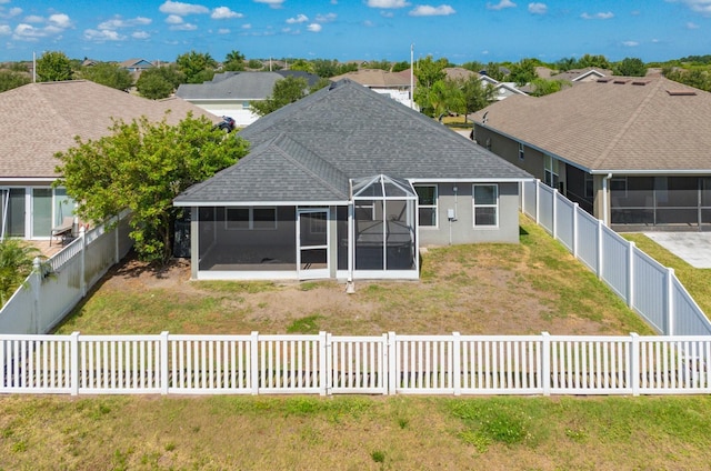 rear view of house featuring a lawn and a sunroom