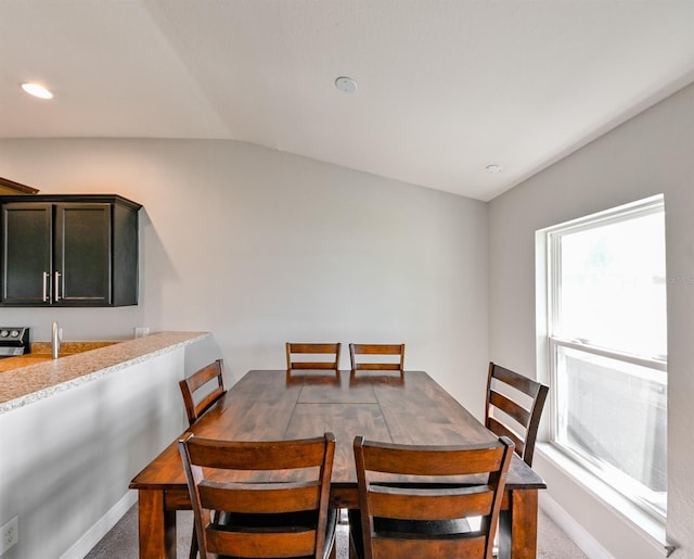 carpeted dining space featuring vaulted ceiling