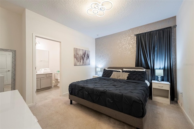 bedroom featuring a textured ceiling, connected bathroom, and light colored carpet