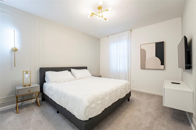 bedroom with a textured ceiling, carpet floors, and a notable chandelier