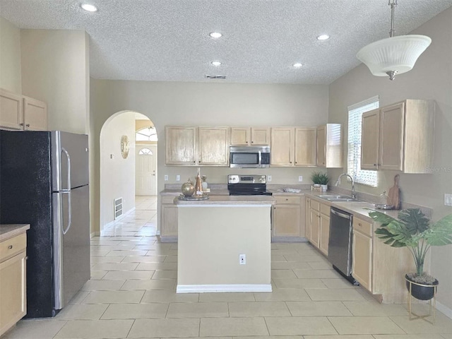 kitchen featuring a kitchen island, appliances with stainless steel finishes, decorative light fixtures, sink, and light brown cabinets