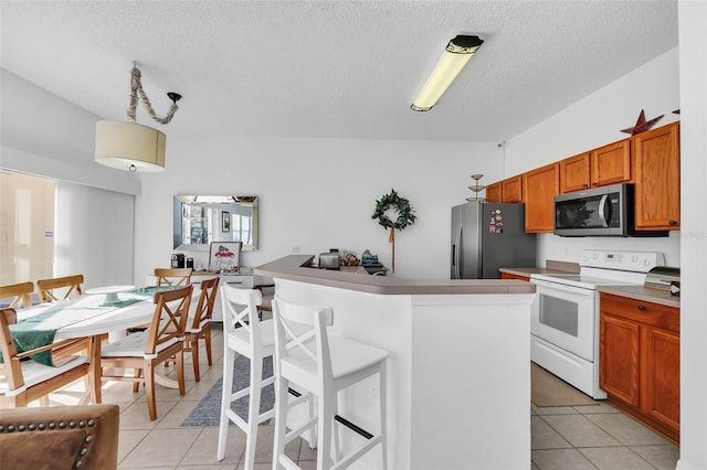 kitchen with a center island, a kitchen bar, stainless steel appliances, and light tile patterned flooring