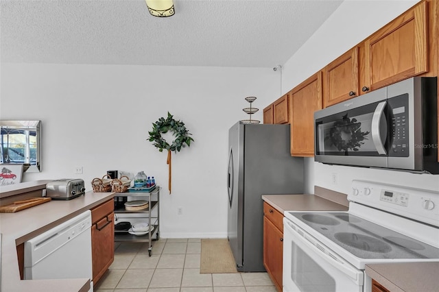 kitchen featuring a textured ceiling, light tile patterned floors, decorative light fixtures, and appliances with stainless steel finishes