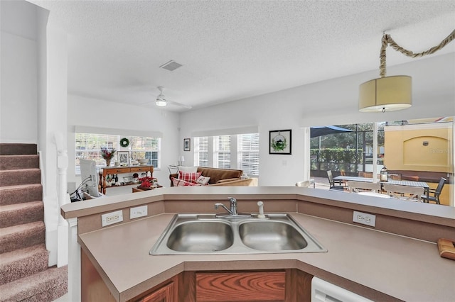 kitchen featuring ceiling fan, sink, white dishwasher, a textured ceiling, and carpet