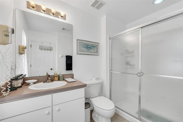 bathroom featuring a shower with door, vanity, and toilet