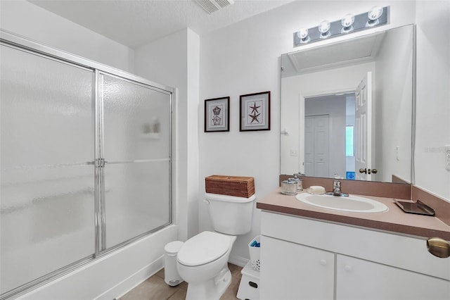 full bathroom featuring tile patterned floors, bath / shower combo with glass door, vanity, a textured ceiling, and toilet