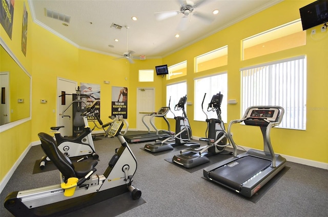 gym with plenty of natural light, ceiling fan, a towering ceiling, and crown molding