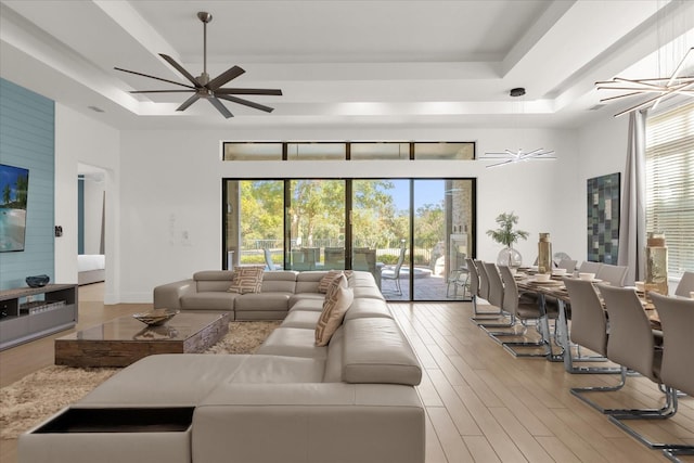 living room with a tray ceiling, plenty of natural light, and light hardwood / wood-style floors