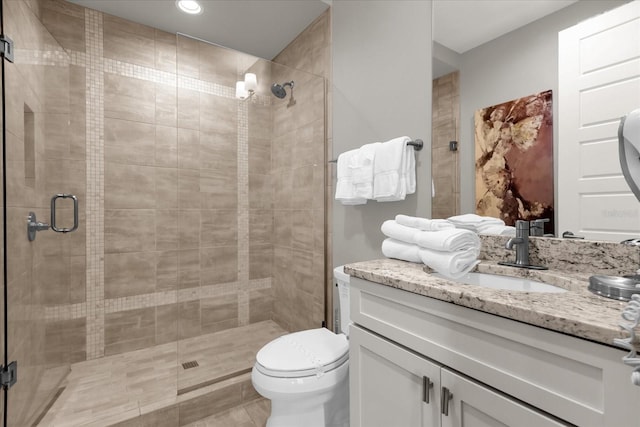 bathroom featuring vanity, toilet, and a shower with door