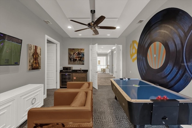 recreation room with dark colored carpet, wine cooler, and ceiling fan