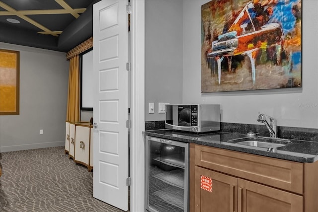 kitchen with dark stone countertops, sink, and beverage cooler