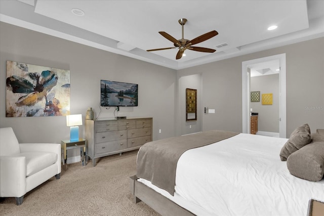 bedroom with light colored carpet, ceiling fan, a tray ceiling, and ensuite bathroom