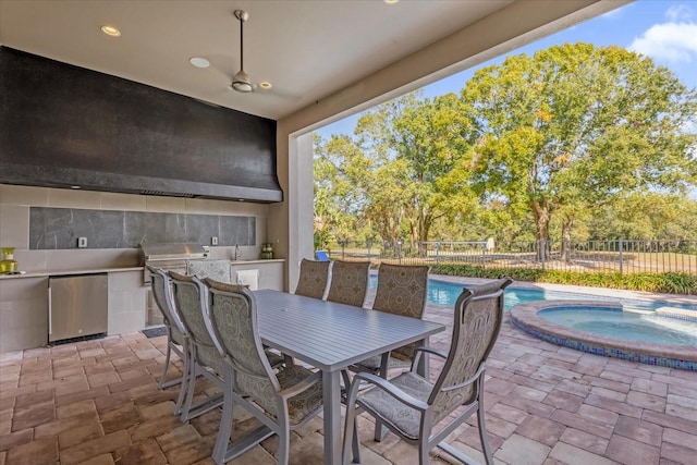 view of patio / terrace with area for grilling and a swimming pool with hot tub