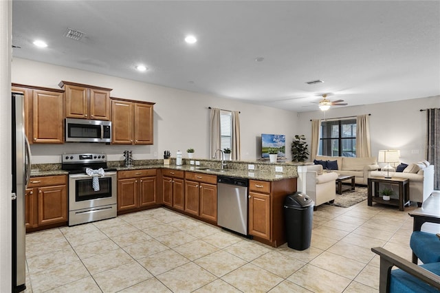 kitchen featuring stainless steel appliances, sink, ceiling fan, light tile patterned floors, and stone countertops