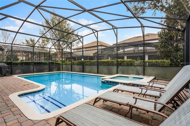 view of swimming pool featuring glass enclosure, an in ground hot tub, and a patio area