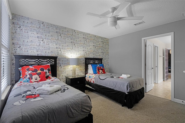 bedroom featuring light colored carpet, ceiling fan, and a textured ceiling