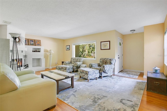 living room featuring hardwood / wood-style flooring, a textured ceiling, and a fireplace