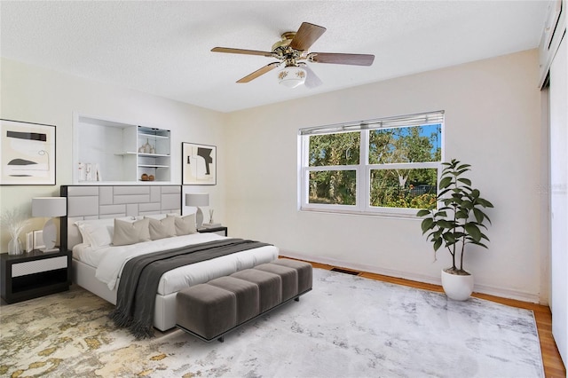 bedroom featuring ceiling fan, light hardwood / wood-style flooring, and a textured ceiling