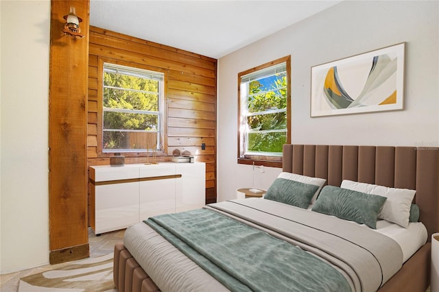 bedroom featuring multiple windows and wood walls