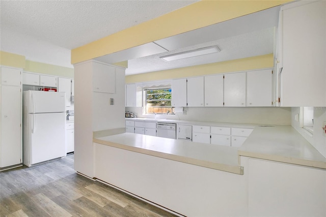 kitchen featuring light wood-type flooring, a textured ceiling, white cabinets, and white appliances