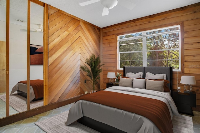 bedroom with ceiling fan and wood walls