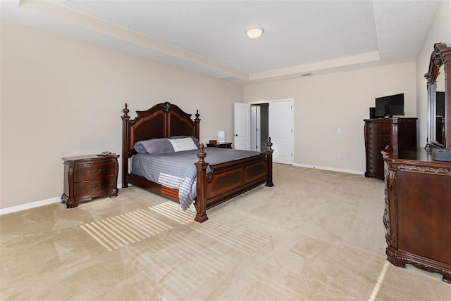 bedroom with light carpet and a tray ceiling