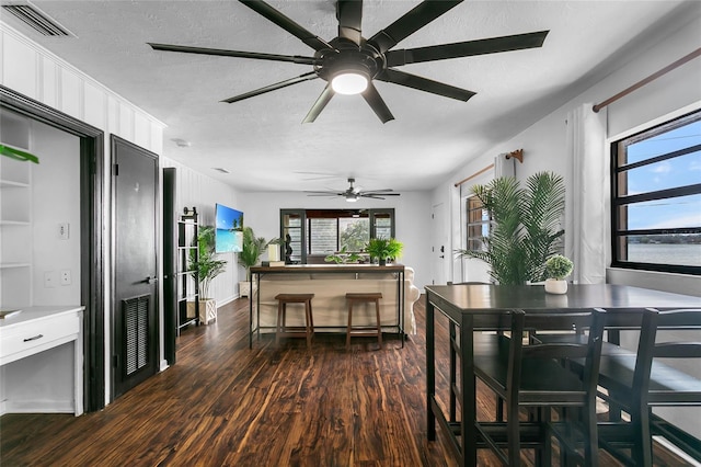 dining room featuring a textured ceiling, plenty of natural light, and dark wood-type flooring