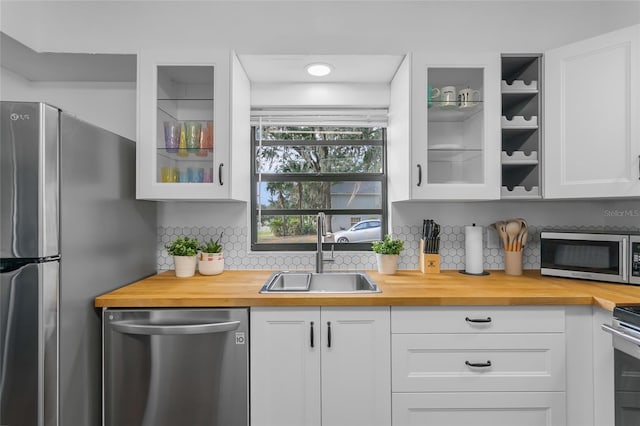 kitchen featuring white cabinetry, sink, backsplash, butcher block countertops, and appliances with stainless steel finishes