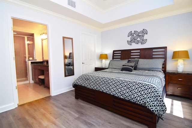 bedroom featuring light wood-type flooring, ensuite bathroom, and crown molding