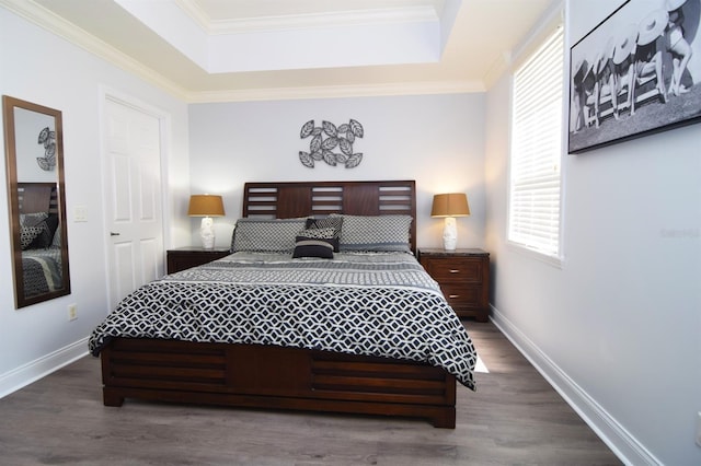 bedroom with dark hardwood / wood-style flooring, a raised ceiling, and ornamental molding