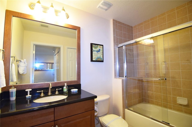 full bathroom featuring a textured ceiling, vanity, toilet, and bath / shower combo with glass door