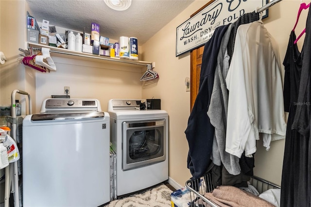 clothes washing area with a textured ceiling and separate washer and dryer