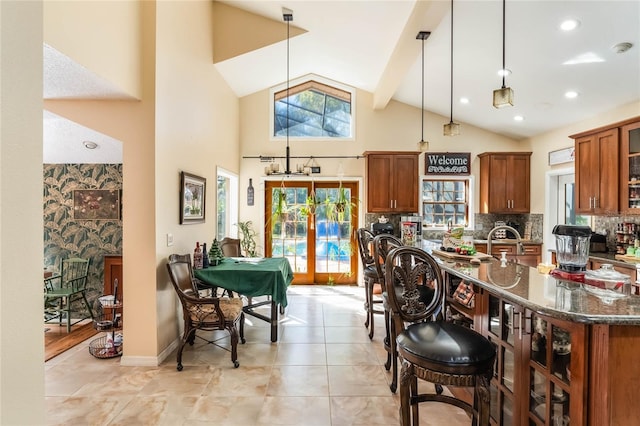 kitchen with backsplash, dark stone counters, pendant lighting, beam ceiling, and high vaulted ceiling