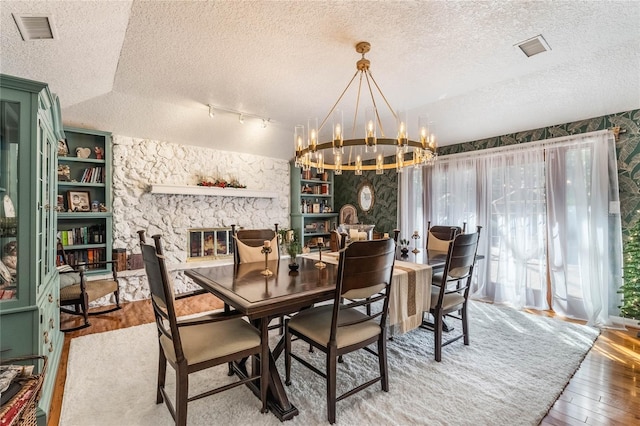 dining space with a fireplace, a chandelier, plenty of natural light, and wood-type flooring