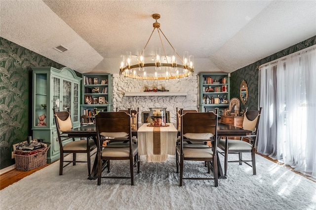 dining area featuring an inviting chandelier, a textured ceiling, vaulted ceiling, a fireplace, and hardwood / wood-style flooring