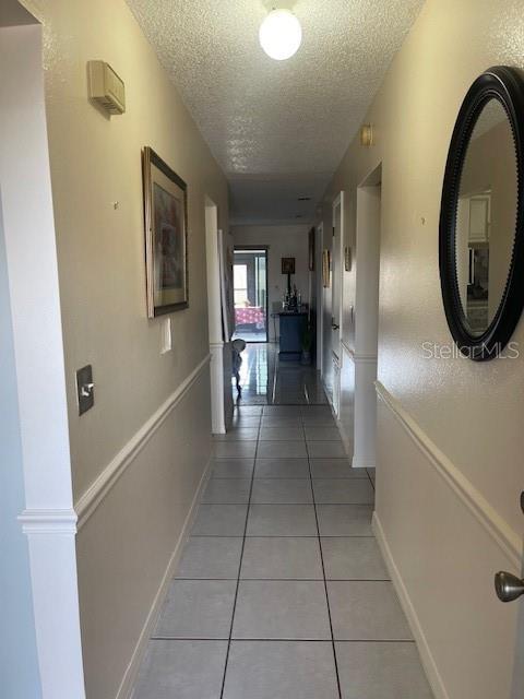 corridor with a textured ceiling and tile patterned floors