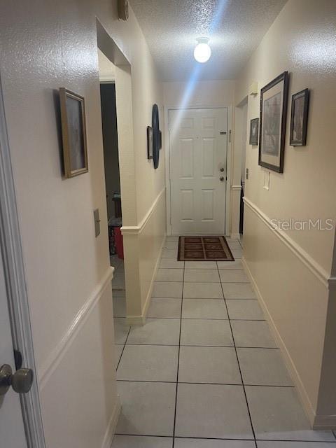 hallway with light tile patterned floors and a textured ceiling