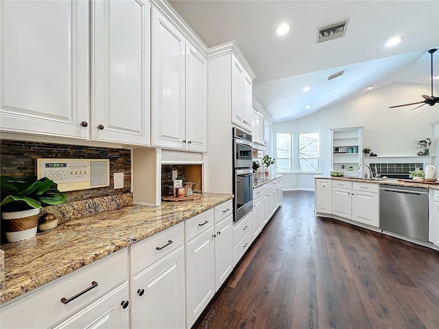 kitchen with dark wood-type flooring, stainless steel appliances, tasteful backsplash, vaulted ceiling, and white cabinets