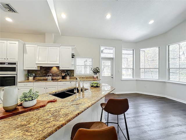 kitchen featuring light stone countertops, sink, backsplash, black electric stovetop, and white cabinets