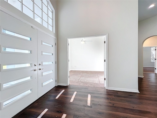 foyer entrance featuring a towering ceiling, dark hardwood / wood-style floors, and ceiling fan