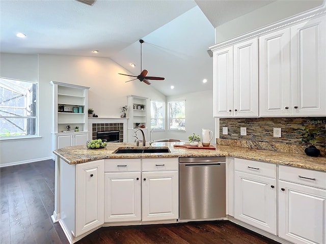 kitchen featuring sink, backsplash, kitchen peninsula, vaulted ceiling, and white cabinets