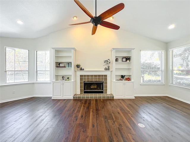 unfurnished living room featuring dark hardwood / wood-style flooring, vaulted ceiling, ceiling fan, and a tiled fireplace