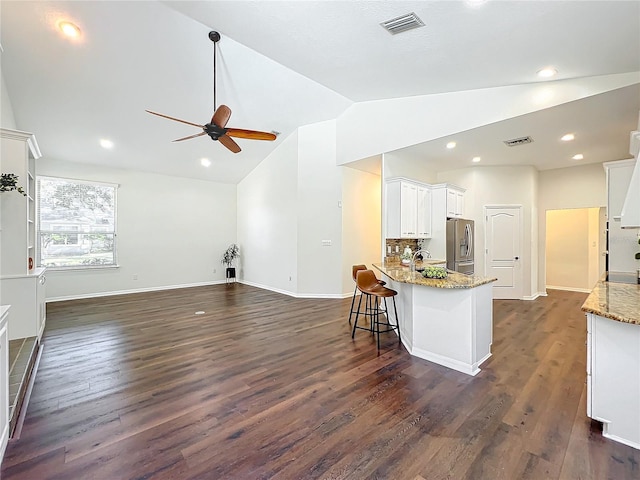 kitchen featuring light stone countertops, sink, dark hardwood / wood-style flooring, stainless steel fridge, and white cabinets