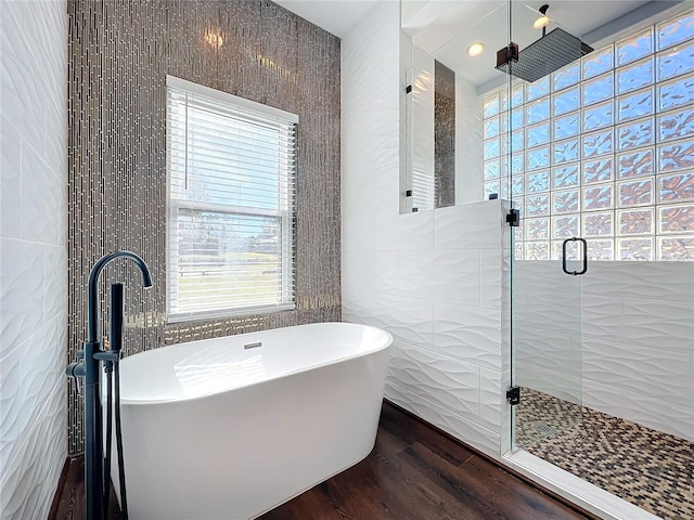 bathroom featuring sink, plus walk in shower, tile walls, and hardwood / wood-style flooring