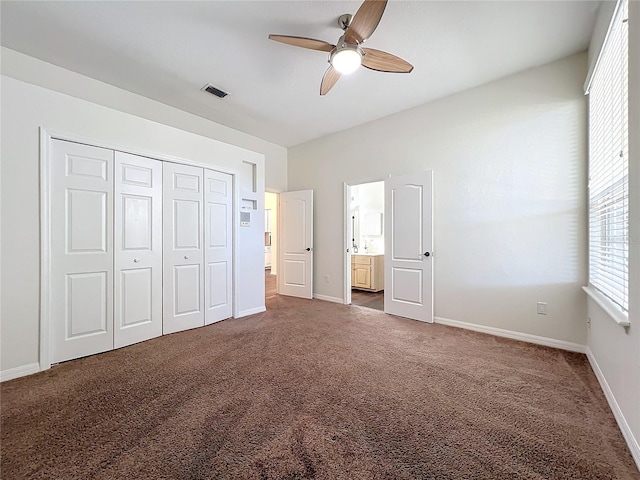 unfurnished bedroom with ensuite bath, ceiling fan, a closet, and dark colored carpet