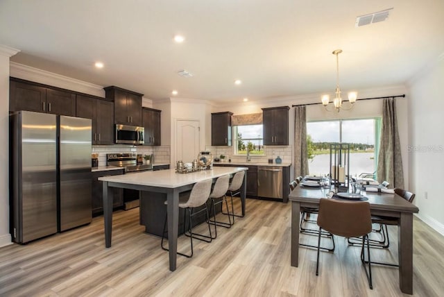 kitchen featuring dark brown cabinets, stainless steel appliances, light hardwood / wood-style flooring, and hanging light fixtures