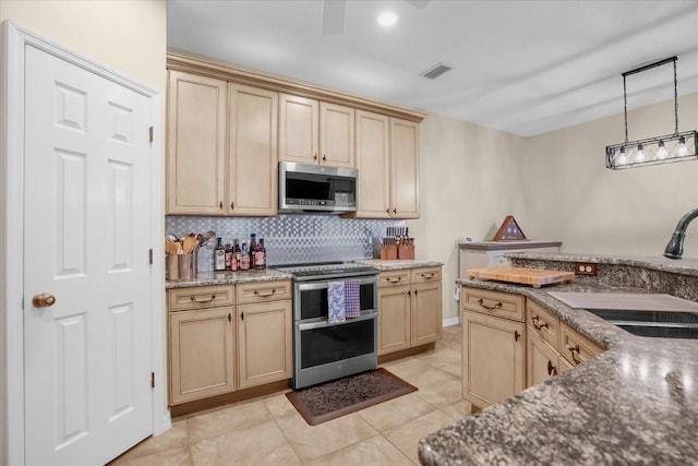 kitchen featuring pendant lighting, sink, dark stone countertops, light tile patterned flooring, and stainless steel appliances