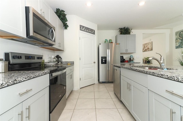 kitchen featuring white cabinets, sink, light stone countertops, light tile patterned floors, and stainless steel appliances