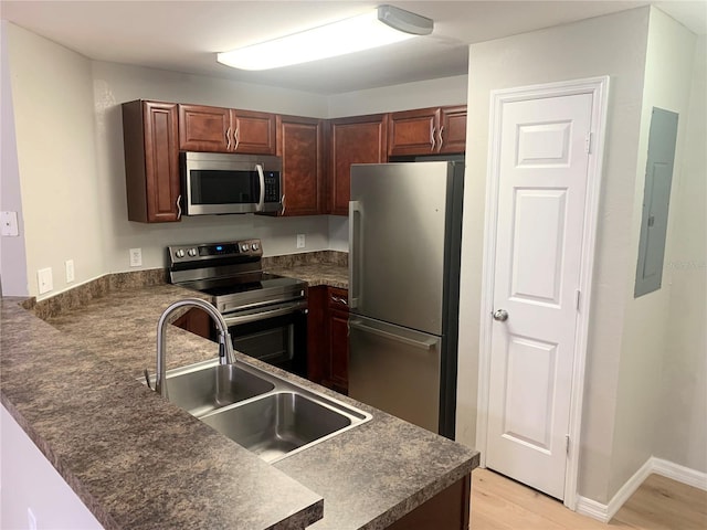 kitchen featuring kitchen peninsula, sink, stainless steel appliances, and light hardwood / wood-style flooring